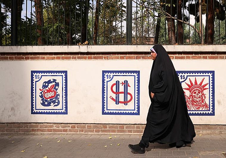 Una mujer pasa junto a un mural antiestadounidense fuera del edificio que anteriormente albergaba la embajada de los Estados Unidos en Teherán