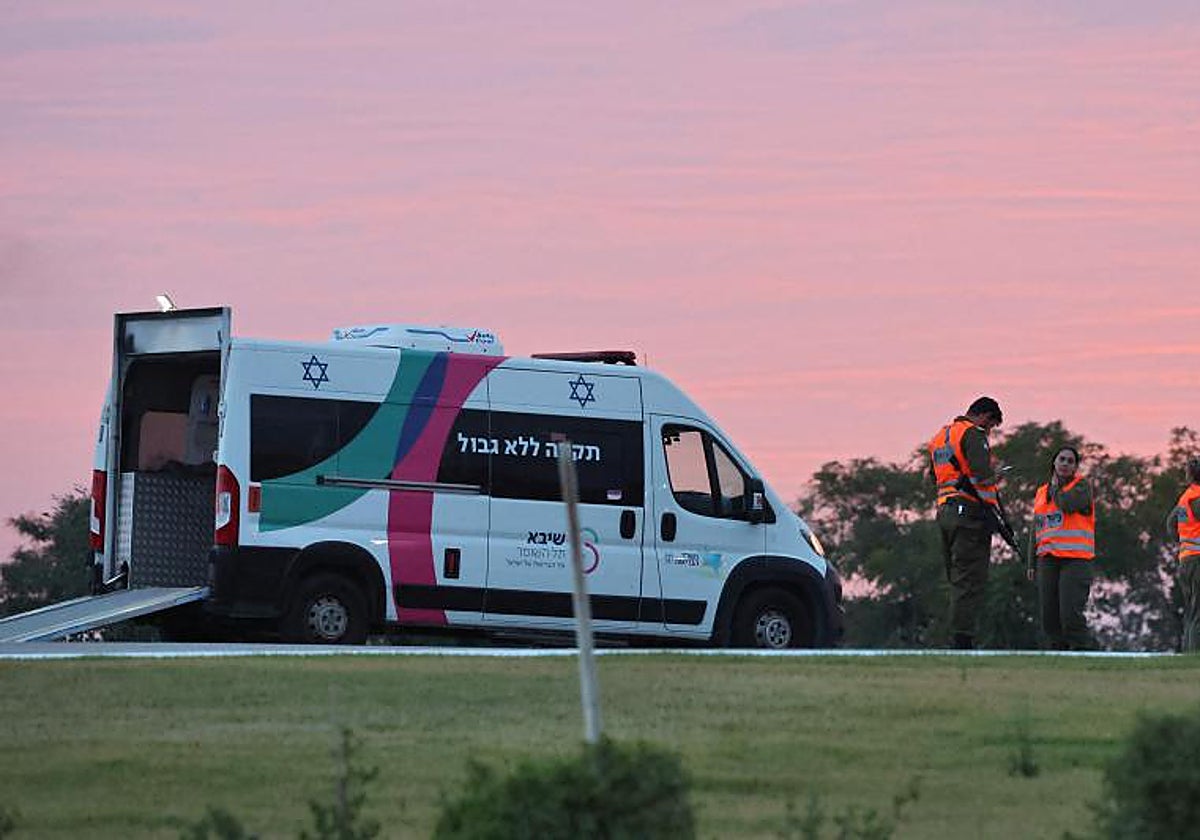 Ls fuerzas de seguridad israelíes se encuentran junto a una ambulancia mientras el personal médico se prepara para la llegada de rehenes israelíes que serán liberados por Hamás