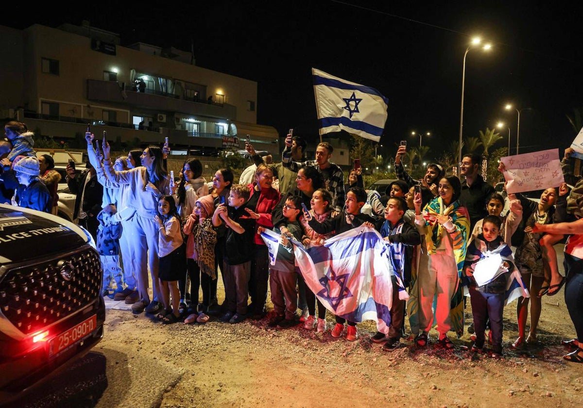 La gente aplaude mientras un vehículo que transporta rehenes liberados por Hamás se dirige hacia una base militar en Ofakim, en el sur de Israel