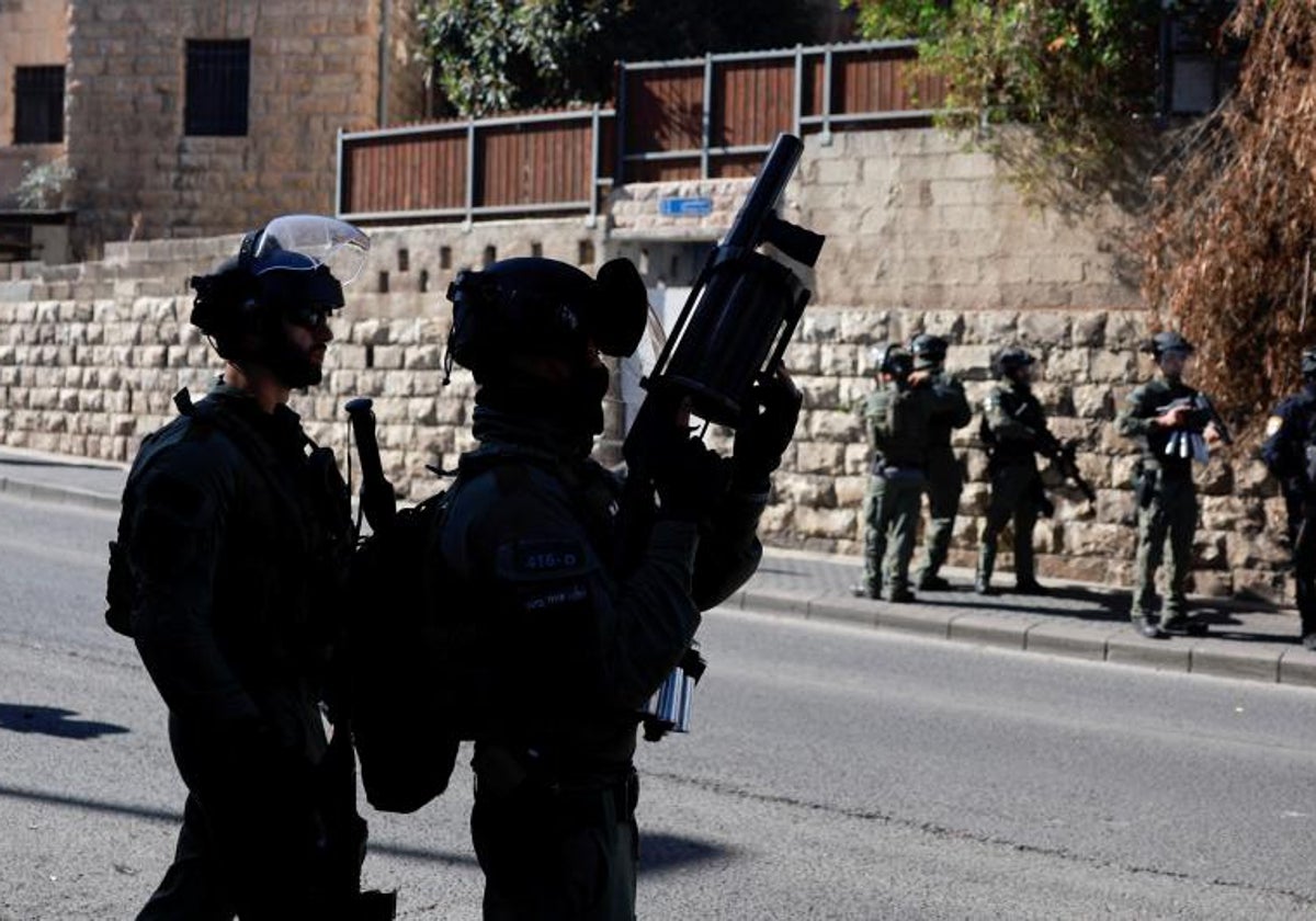 Oficiales de la policía fronteriza israelí hacen guardia mientras los palestinos musulmanes intentan realizar las oraciones del viernes en una carretera en las afueras de la Ciudad Vieja de Jerusalén