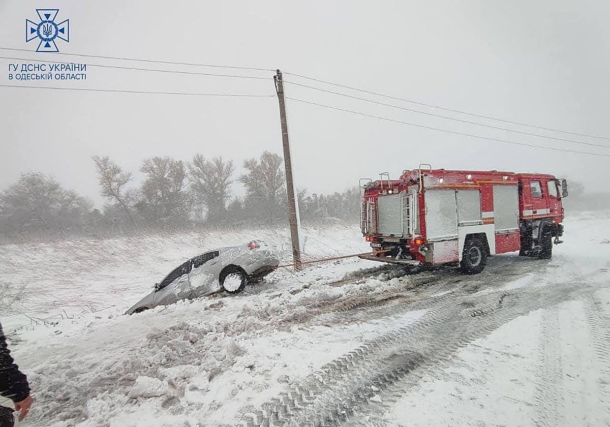 Los trabajadores de emergencia liberan un coche atascado en la nieve durante una fuerte tormenta en Odesa