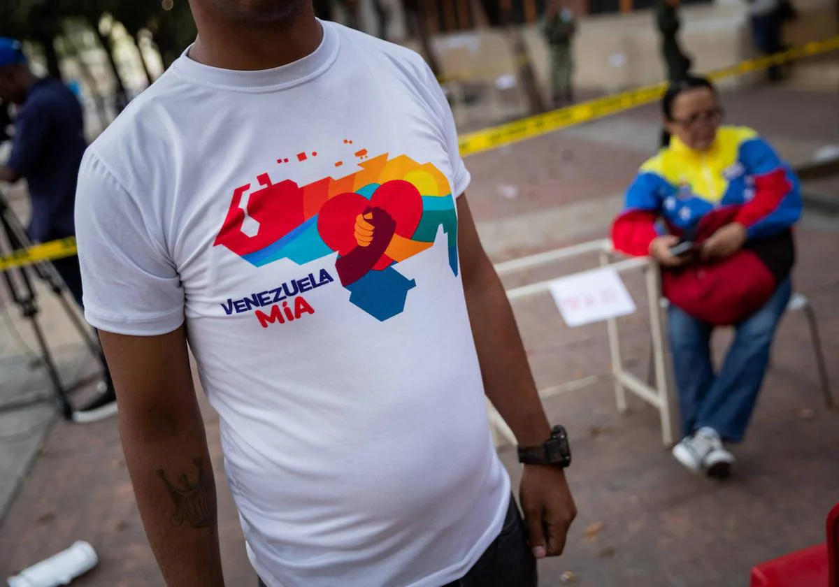 Un seguidor del Gobierno viste una franela con el mapa de Venezuela que dice «Venezuela mía» frente a un centro de votación