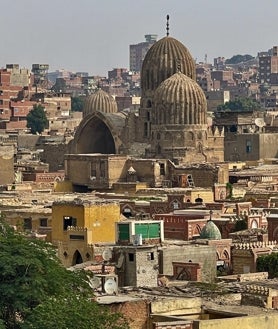 Imagen secundaria 2 - Los cementerios históricos de El Cairo, donde despuntan sus panteones con las típicas cúpulas bulbosas islámicas, están rodeados de bloques de viviendas y chabolas por el caótico desarrollismo de El Cairo (imagen superior). Muchas de sus tumbas, algunas con siglos de antigüedad, están siendo destruidas para construir avenidas y autopistas elevadas (arriba a la izquierda), mientras que algunos mausoleos se han convertido en infraviviendas (arriba a la derecha). 