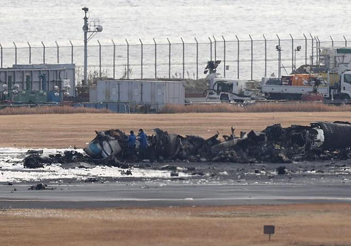Investigadores de la Policía Metropolitana de Tokio ante los restos del avión de la Guardia Costera calcinado