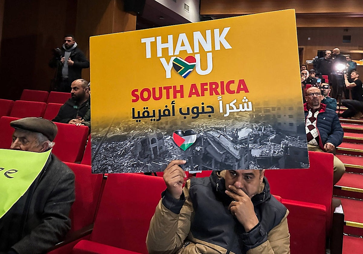 Un hombre sostiene en una sala de Cisjordania un cartel de agradecimiento a Sudáfrica por abrir la causa contra Israel