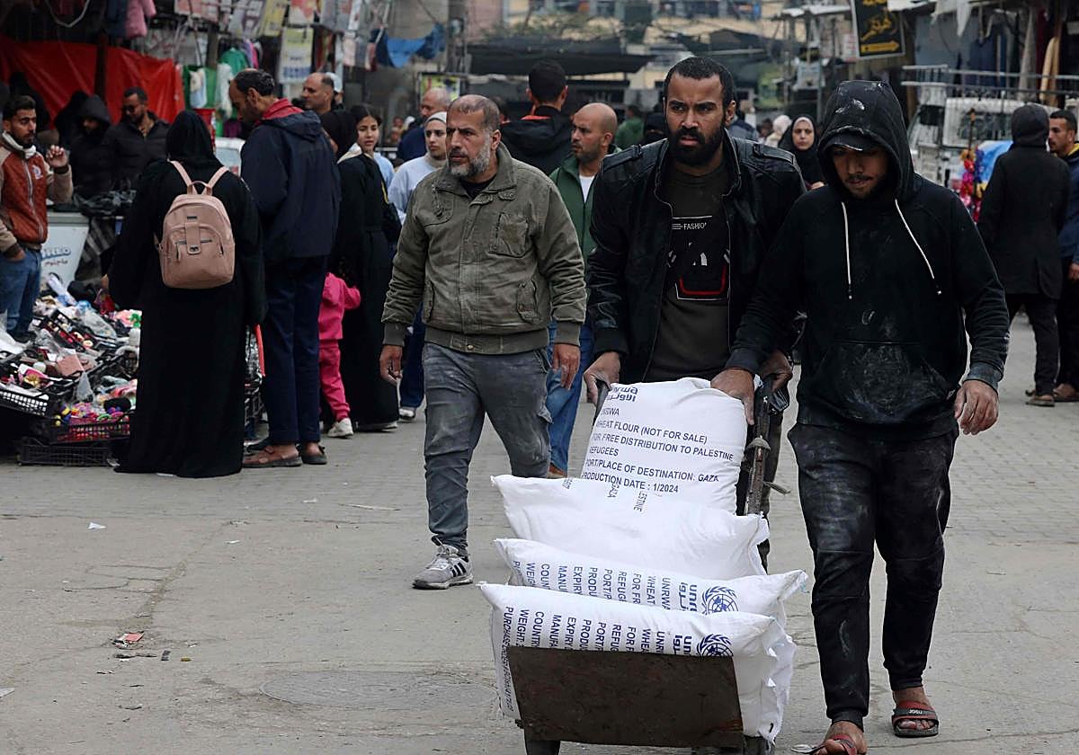 Varios palestinos con una carretilla cargada con sacos de harina