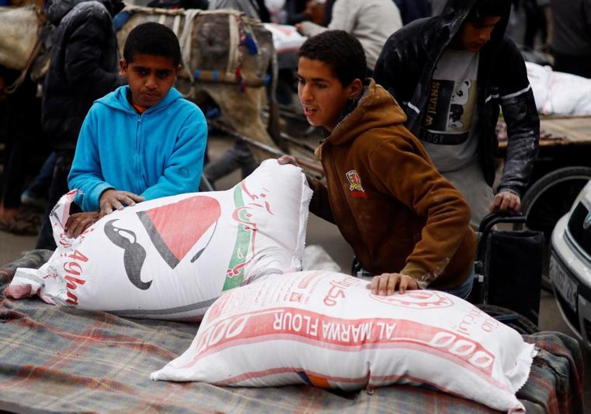 Un niño palestino almacena bolsas de harina distribuidas por la Unrwa