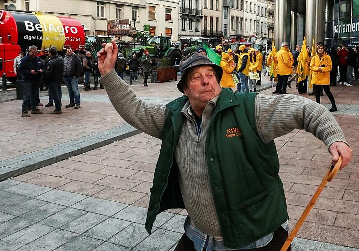 Un agricultor lanza un huevo a los agentes de policía durante unas protestas que buscan bloquear el exterior de la sede de la Unión Europea