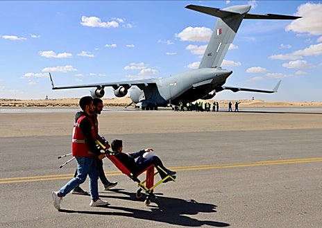 Imagen secundaria 1 - Cientos de camiones cargados con ayuda humanitaria hacen cola para entrar en Gaza por el paso fronterizo de Rafah (imagen superior), lo que Egipto achaca a los controles israelíes. Por este cruce no solo llega la asistencia a los palestinos, sino que también salen los heridos evacuados a hospitales de Egipto y otros países. Estos últimos son trasladados desde el cercano aeropuerto de El Arish (arriba a la izquierda), como Amina, una niña de 13 años que perdió a su padre en un bombardeo israelí y será tratada de la sangre que se le acumula en los ojos en Qatar (arriba a la derecha).  