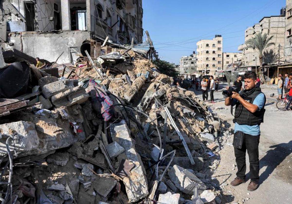 El fotógrafo de la AFP, Said Khatib, fotografía con su cámara el lugar donde se derrumbó un edificio tras los bombardeos israelíes en Rafah, en el sur de la Franja de Gaza