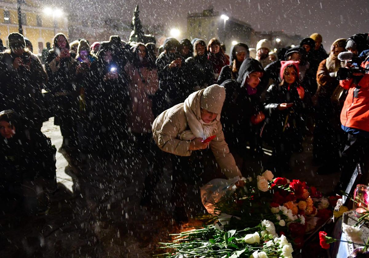 Varias personas llevan flores al monumento de las víctimas de la represión política el día de la muerte de Navalni en Moscú