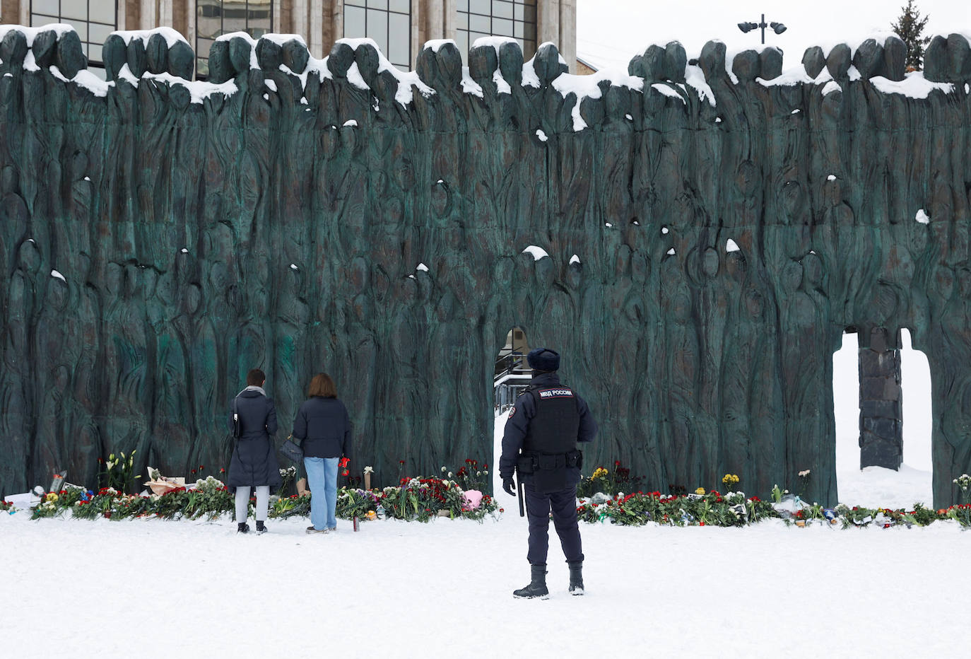 Un oficial de policía hace guardia mientras la gente deposita flores en el monumento del Muro del Dolor a las víctimas de la represión política, en Moscú