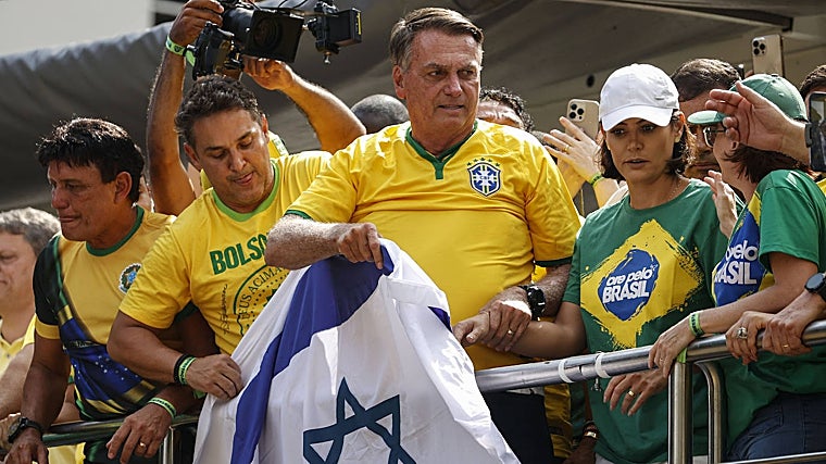 Jair Bolsonaro, acompañado de su esposa, Michelle, sostiene una bandera israelí