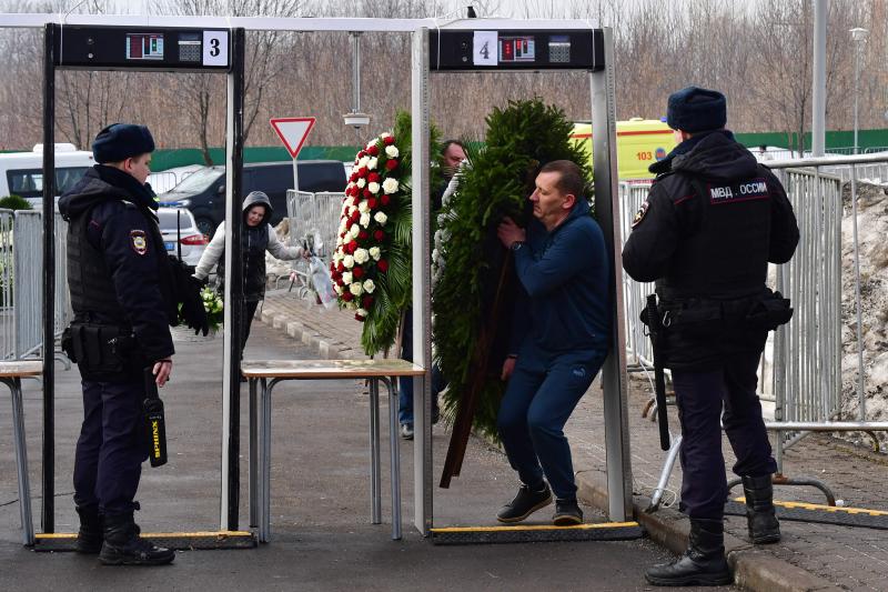 Un hombre que lleva una corona de flores pasa a través de una puerta de seguridad con detector de metales en el cementerio de Borisovo antes del entierro Navalni