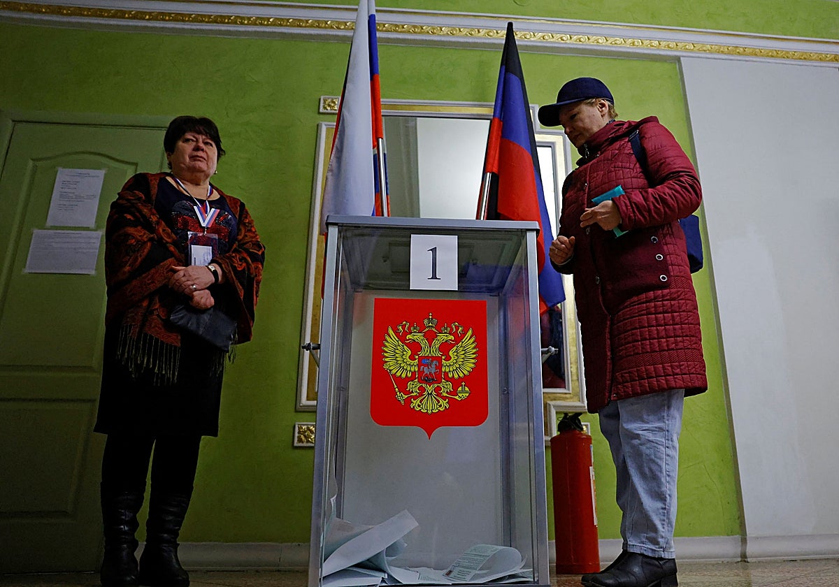 Una mujer deposita su voto en una mesa electoral durante las elecciones presidenciales de Rusia en Donestk