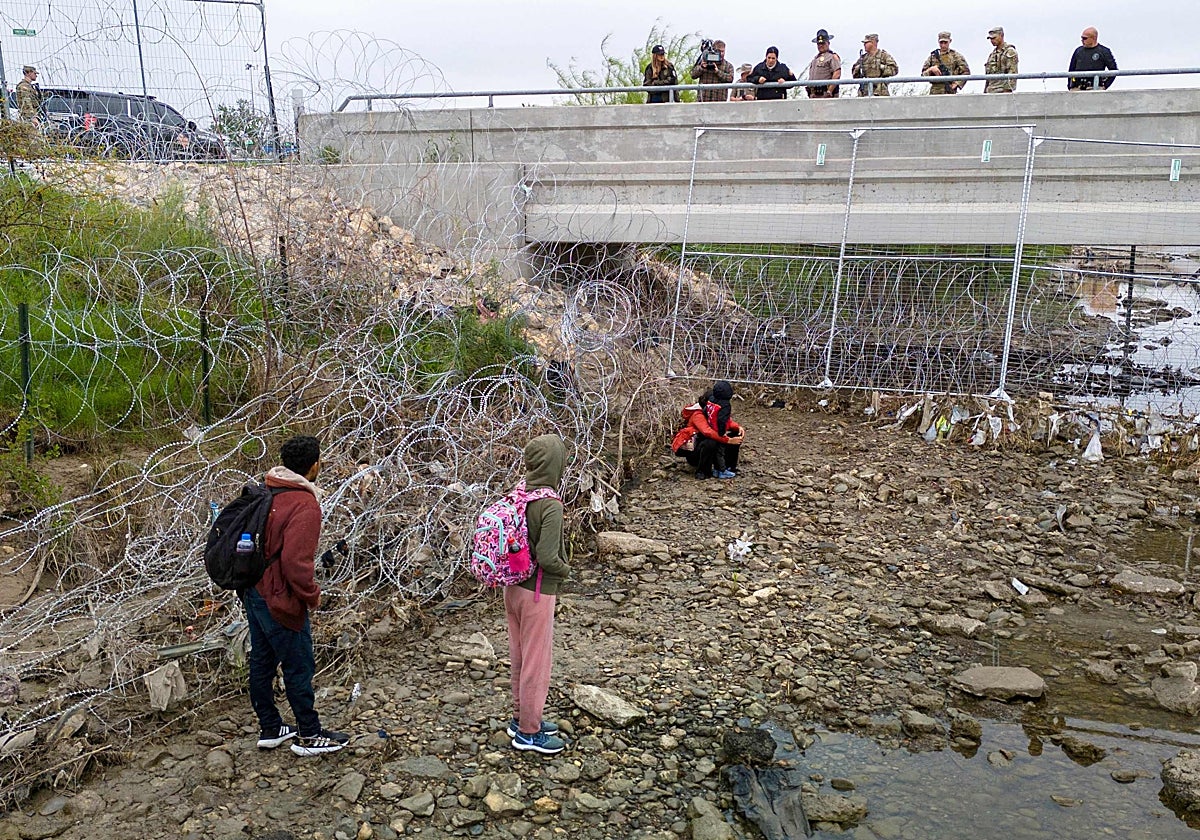 Varias miembros de las fuerzas del orden de EE.UU. vigilan a un grupo de inmigrantes que cruzó el Río Bravo