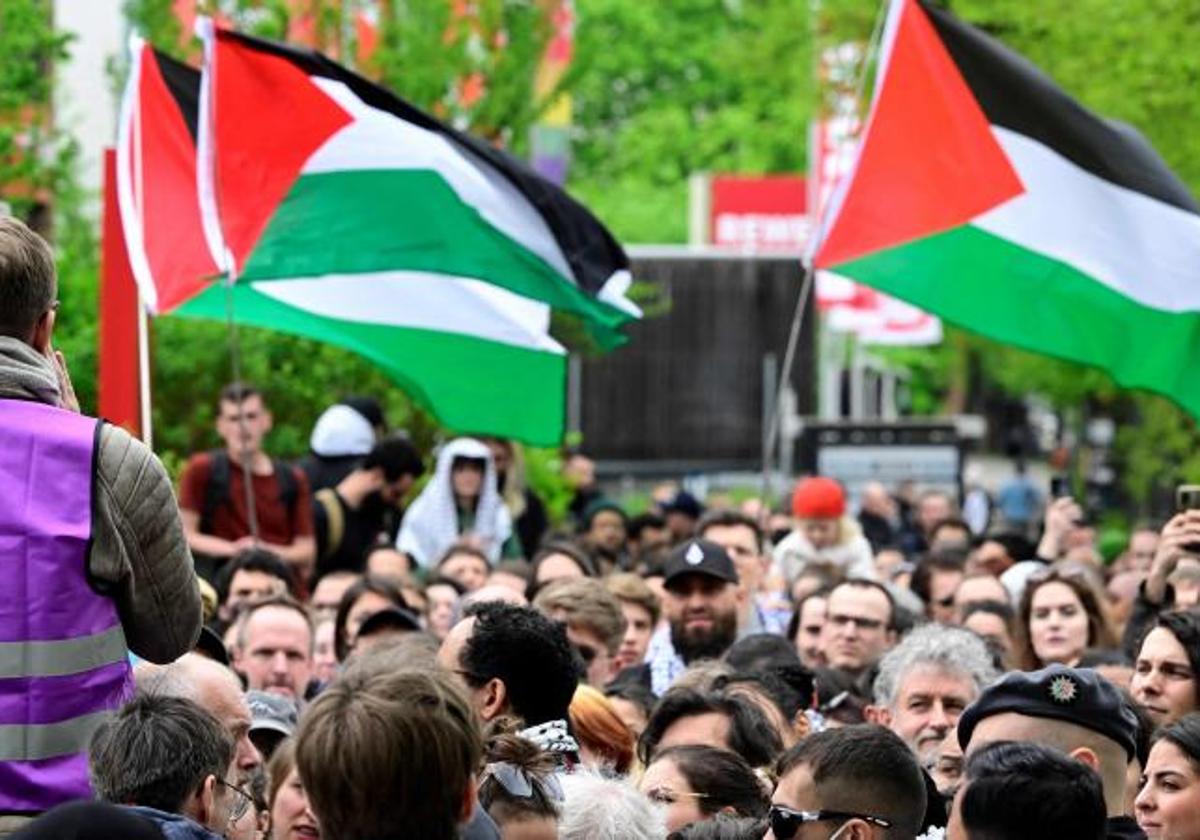 La gente ondea banderas palestinas mientras espera frente al lugar de celebración de la llamada Conferencia Palestina