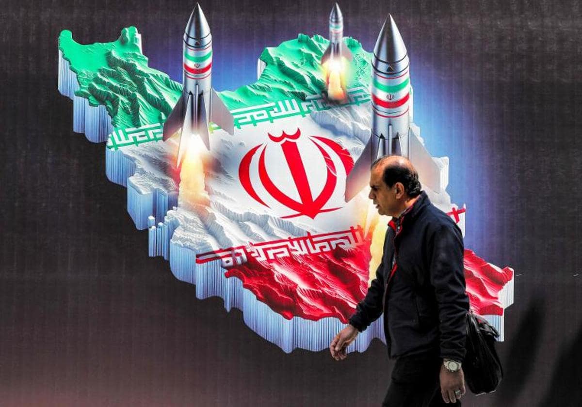 Un hombre pasa junto a una pancarta que representa el lanzamiento de misiles desde Irán