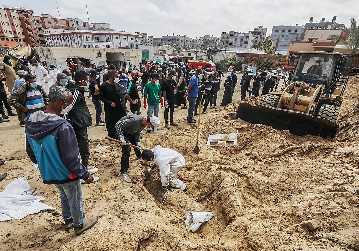 Trabajadores sanitarios palestinos desentierran cadáveres de palestinos enterrados en el recinto del Hospital Nasser