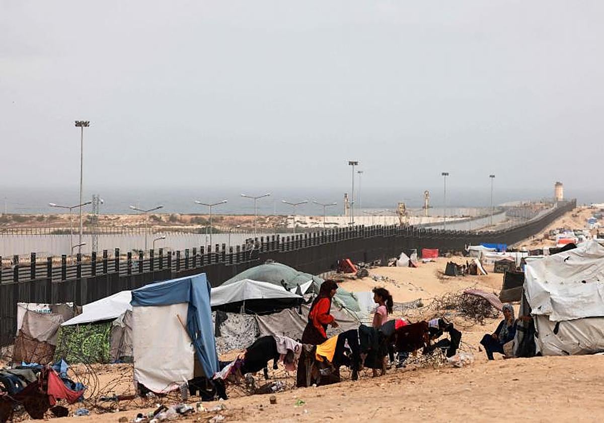 Los palestinos desplazados se sientan afuera para escapar del calor abrasador en sus tiendas de campaña en Rafah, en el sur de la Franja de Gaza, cerca de la frontera con Egipto
