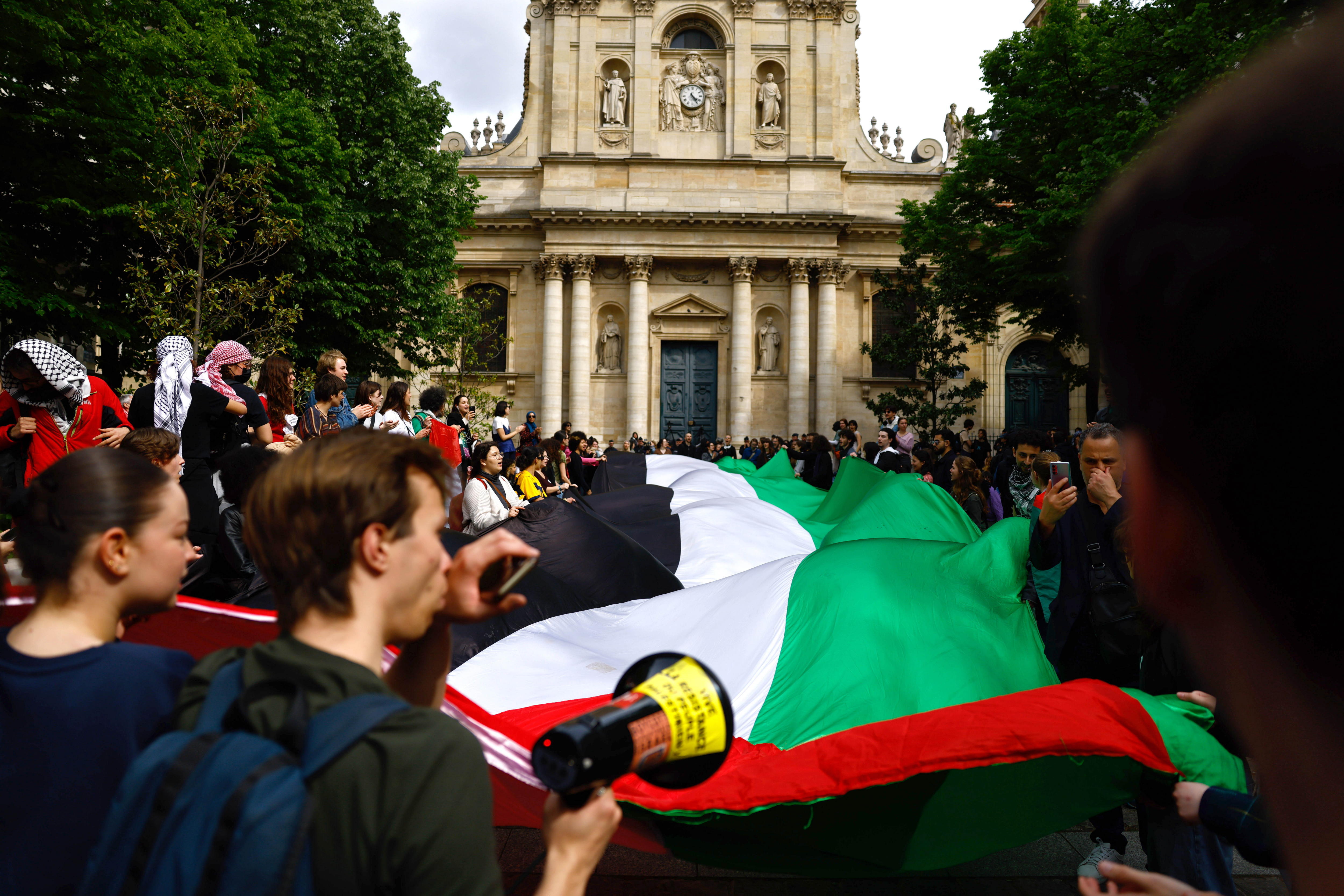 Manifestantes portan una enorme bandera palestina mientras se reúnen frente a la Universidad de la Sorbona en París
