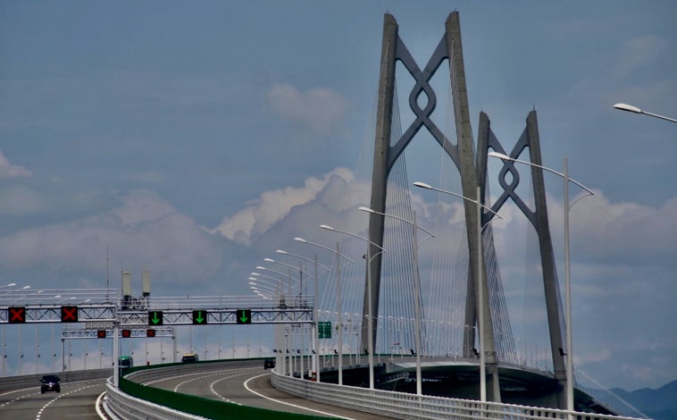 Imagen principal - Conectada por trenes de alta velocidad, autopistas de dos niveles y barcos que surcan el delta del río de las Perlas, la Gran Bahía es una futurista zona metropolitana con prodigios de la ingeniería como el Puente Hong Kong-Macao-Zhuhai, que es el más largo del mundo sobre el mar con 55 kilómetros y un túnel submarino (imagen superior). Entre las ciudades que forman parte de la Gran Bahía destaca Shenzhen, que en los años 80 era un pueblo de pescadores y, gracias a la apertura de China al capitalismo, se ha convertido en su capital tecnológica (arriba a la izquierda). Por su parte, la capital provincial, Cantón (Guangzhou), es otro de los epicentros mundiales del comercio y tiene como símbolo una torre homónima de 604 metros de altura (arriba a la derecha) 