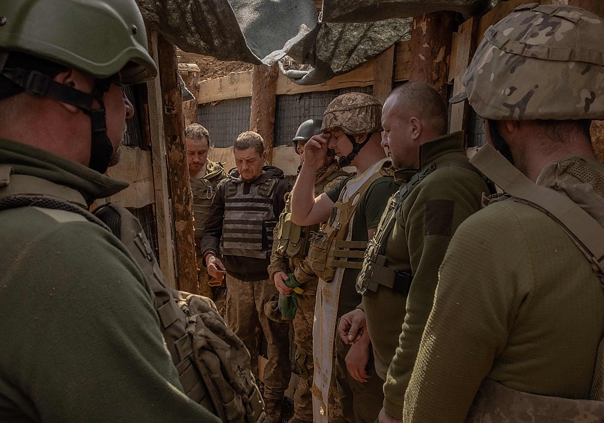 Varios soldados ucranianos se santiguan en una trinchera de la línea de frente de Donetsk