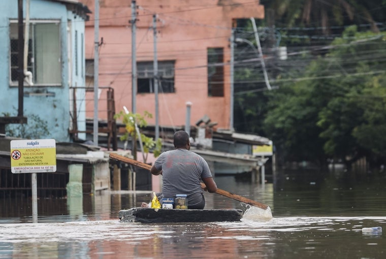 Un hombre se transporta sobre una tabla en una calle inundada, en el barrio de Humaita, Porto Alegre