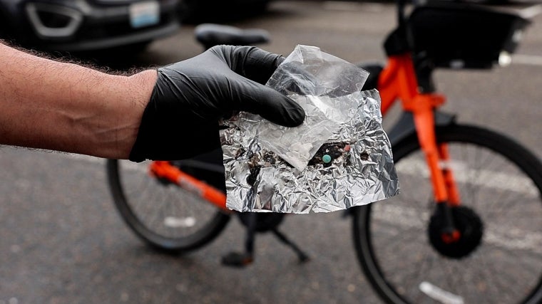 Un oficial de la policía de Portland sostiene una pastilla azul de oxicodona y una pequeña bolsa de fentanilo.