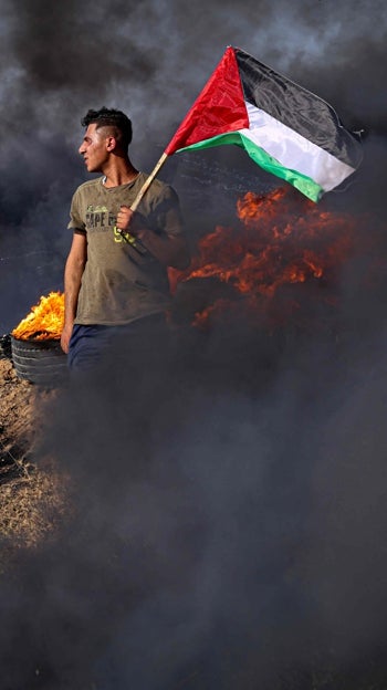Un joven palestino sostiene una bandera durante una protesta junto a la valla fronteriza con Israel, en julio de 2023