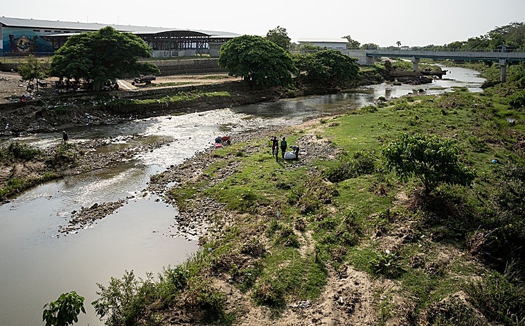 Imagen principal - El río Masacre, la frontera entre Haití y la República Dominicana. Debajo, grupos de personas que recorren la zona