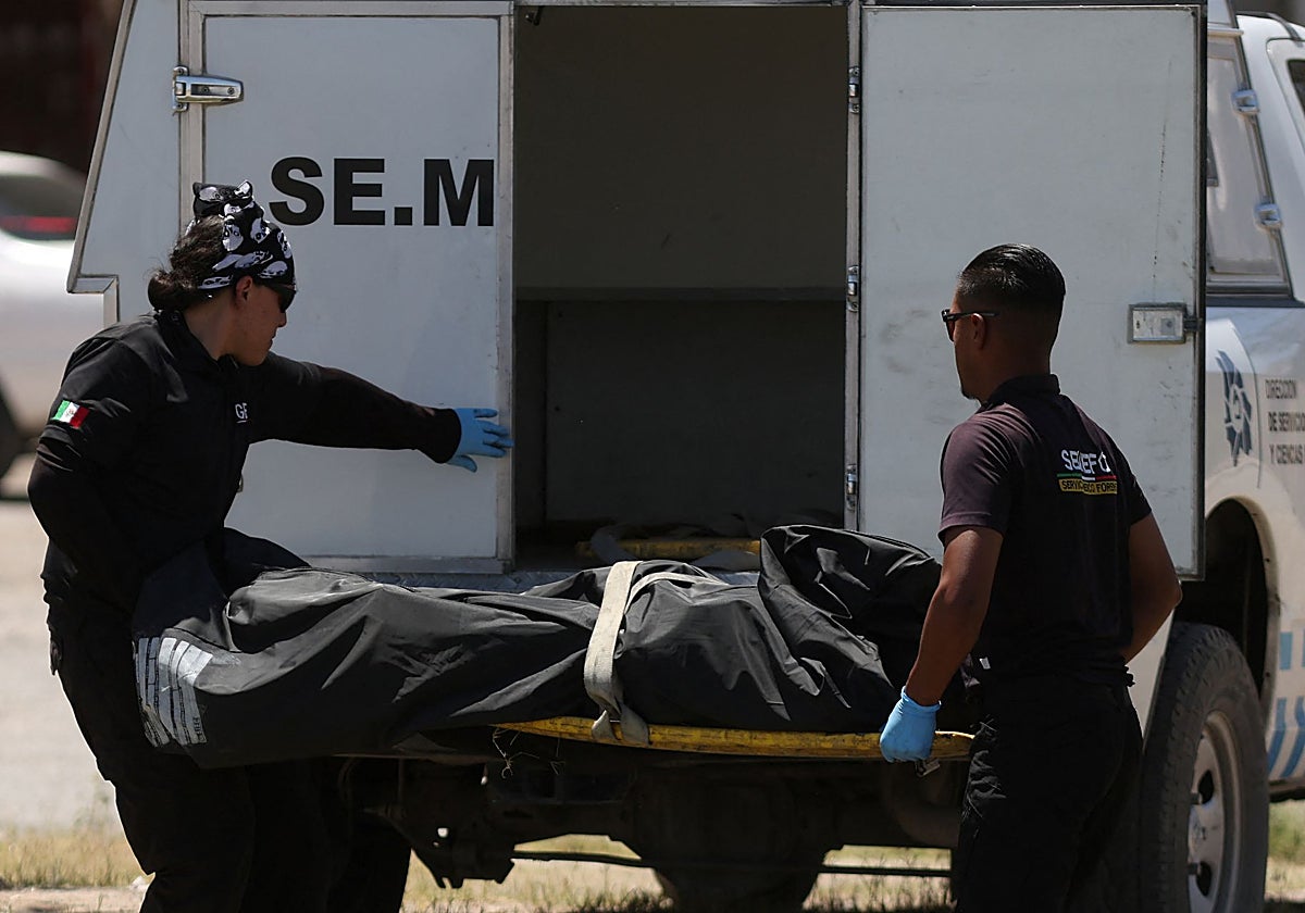 Técnicos forenses recogen el cuerpo de una persona que fue asesinada y quemada por asaltantes desconocidos en un parque, según medios locales, en Ciudad Juárez
