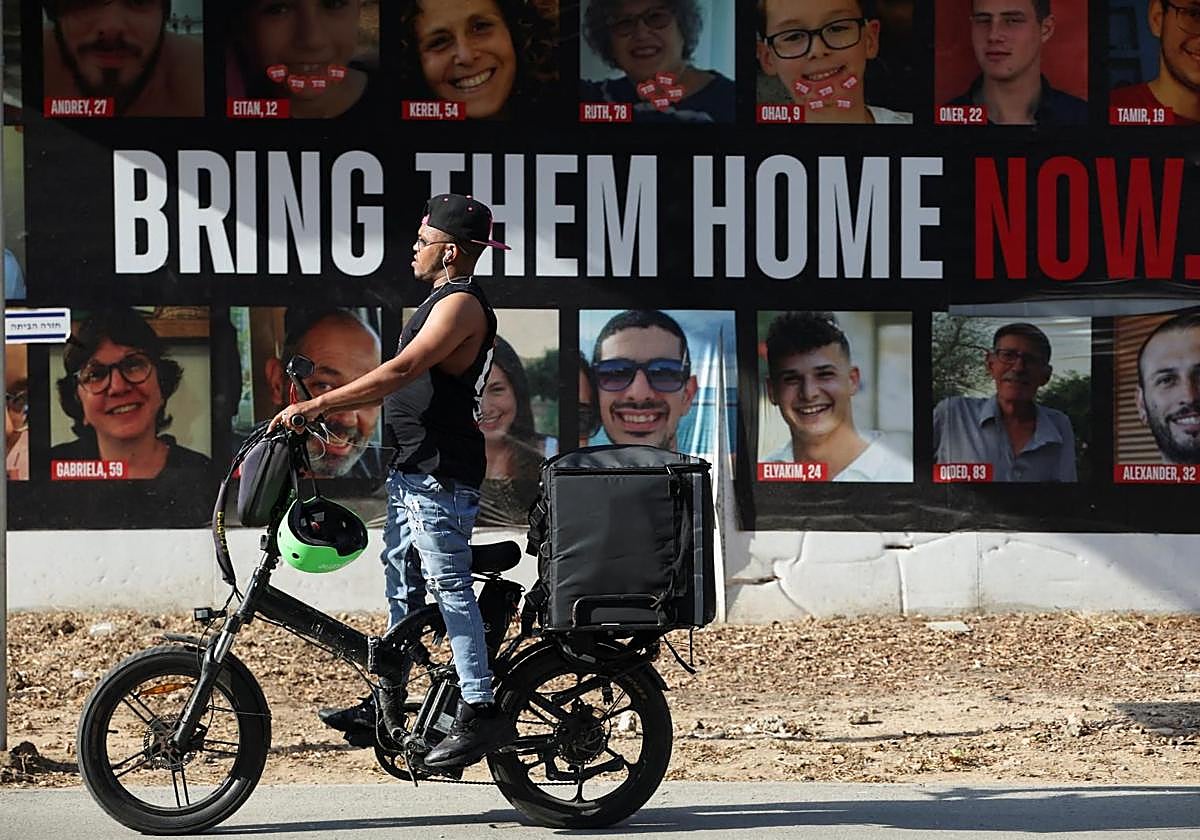 Un hombre pasa junto a fotografías de rehenes secuestrados durante el ataque de Hamás el 7 de octubre