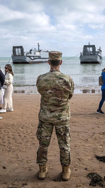 Un militar estadounidense y varios civiles en una playa de Normandía