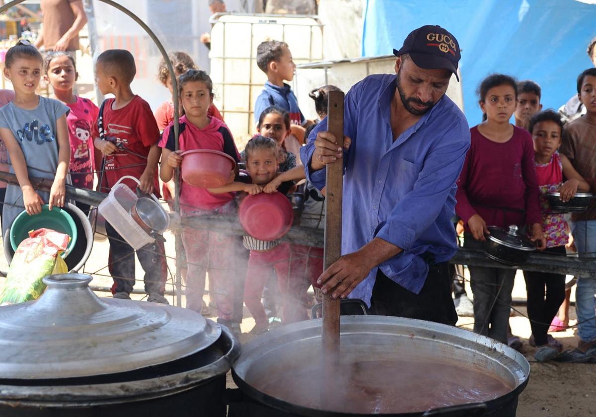 Unos niños esperan a que se distribuyan alimentos en un campamento para desplazados en Gaza