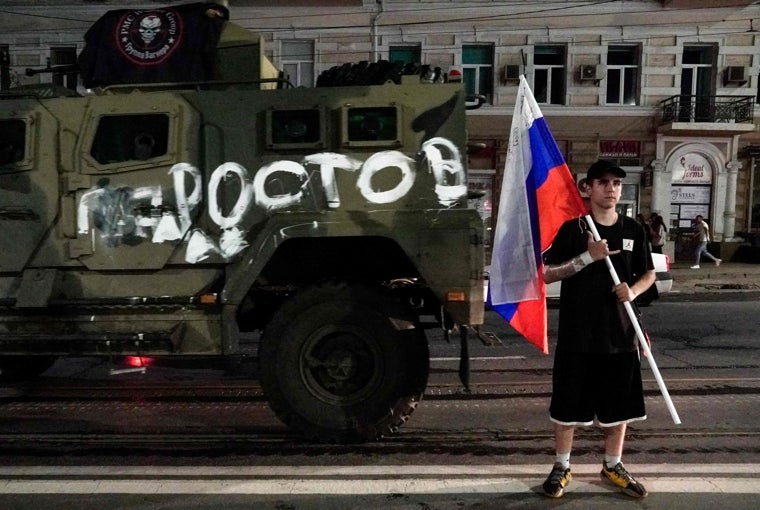 Un hombre sostiene la bandera nacional rusa frente a un vehículo militar del grupo Wagner con el cartel que dice «Rostov» en Rostov del Don, tras el motín