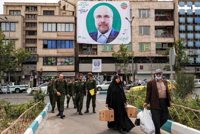 La gente pasa junto a un cartel electoral del candidato presidencial iraní Mohammad Bagher Ghalibaf colgado en la fachada de un edificio en Teherán