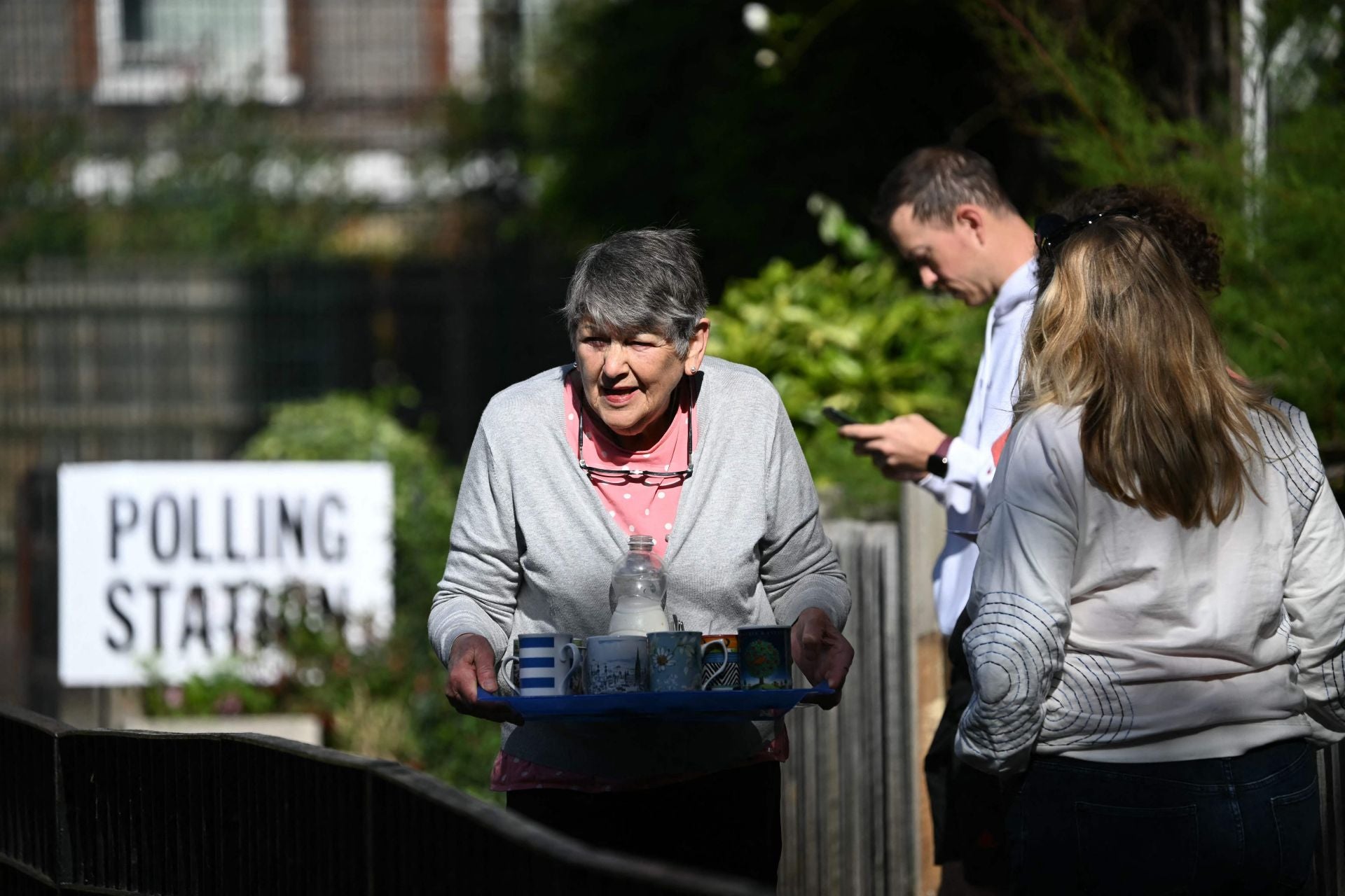 Una residente ofrece té a los votantes que hacen cola fuera de un colegio electoral en Londres