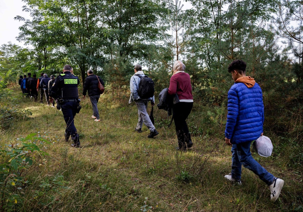 Un grupo de inmigrantes camina por un bosque de Alemania en compañía de la Policía