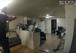 El agente apuntando con la pistola a la mujer afroamericana dentro de su propia casa