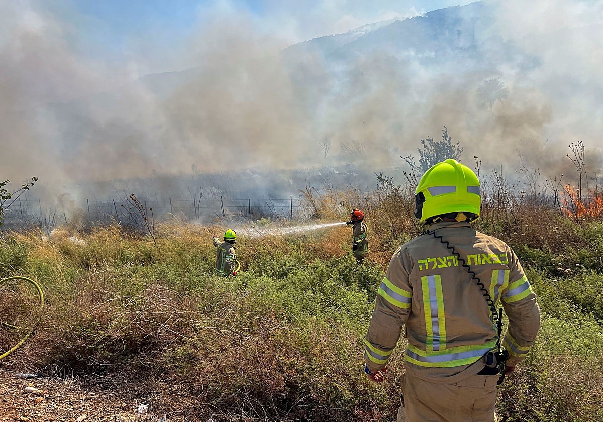 Bomberos israelíes extinguen un fuego causado por el impacto de misiles de Hizbolá