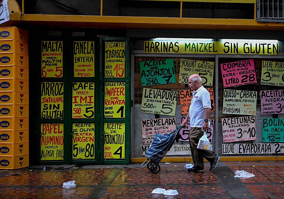 Los residentes pasan frente a un supermercado que exhibe carteles con precios de productos en dólares estadounidenses en Caracas
