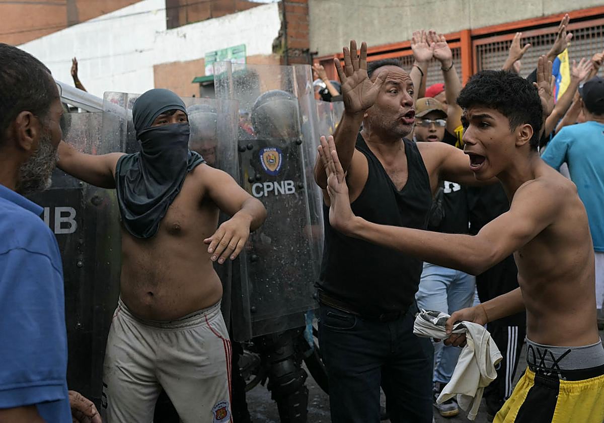 Manifestantes tratan de calmarse unos a otros en una protesta contra Nicolás Maduro tras las elecciones