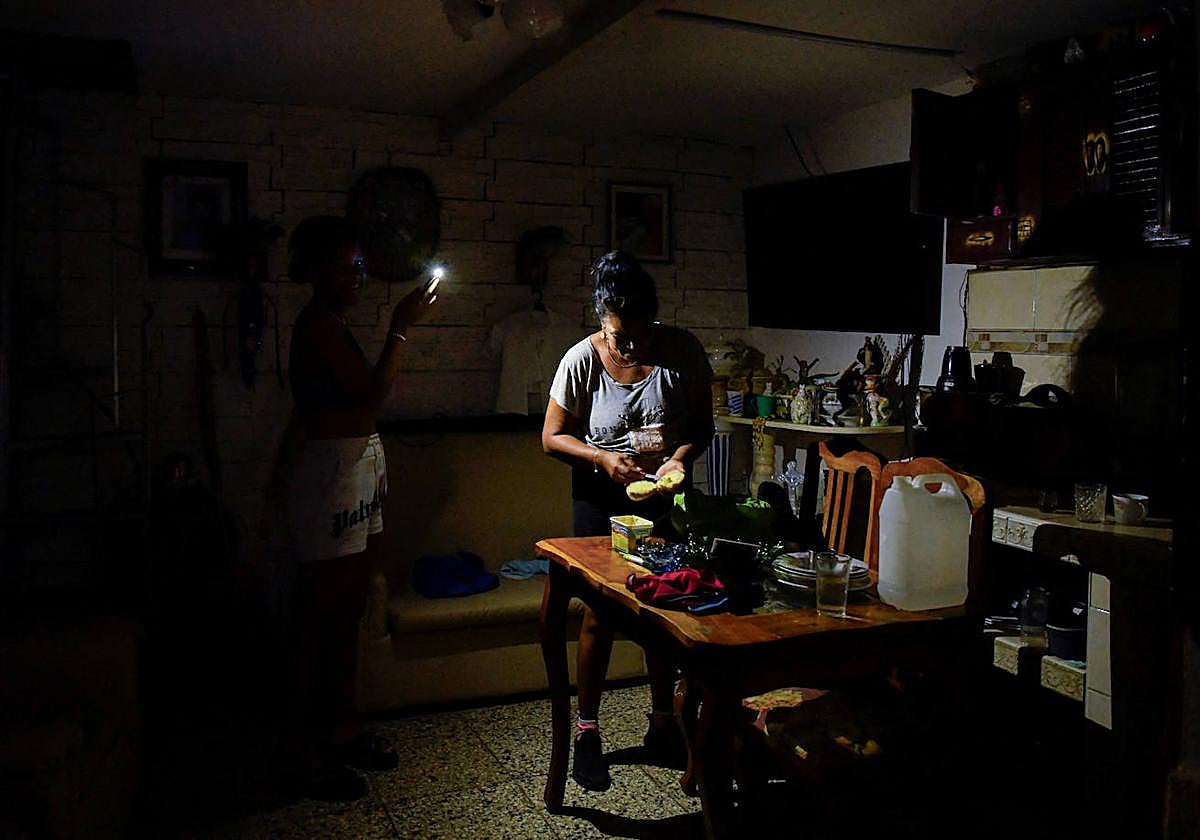 Una mujer prepara comida a la luz de un teléfono móvil durante el apagón
