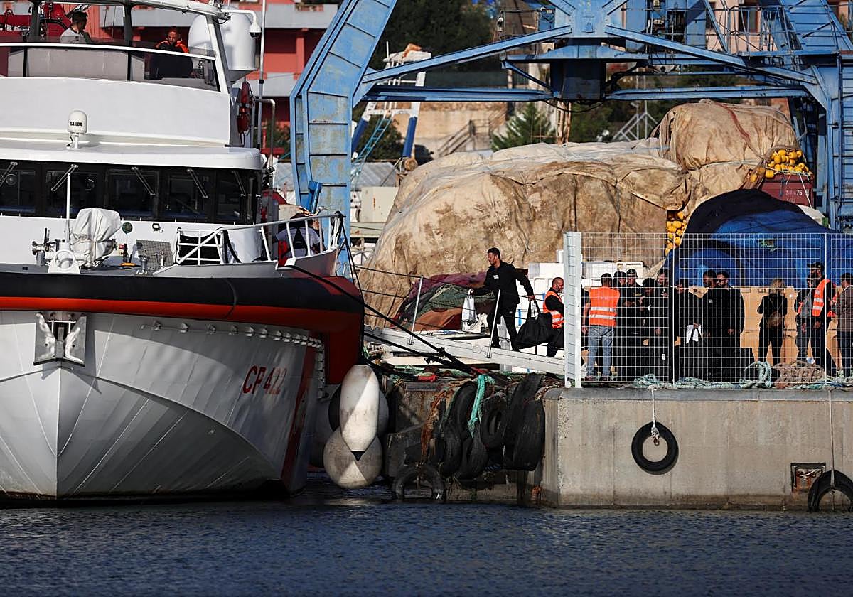 Los inmigrantes trasladados a Albania subiendo a un buque de la Guardia Costera para volver a Italia