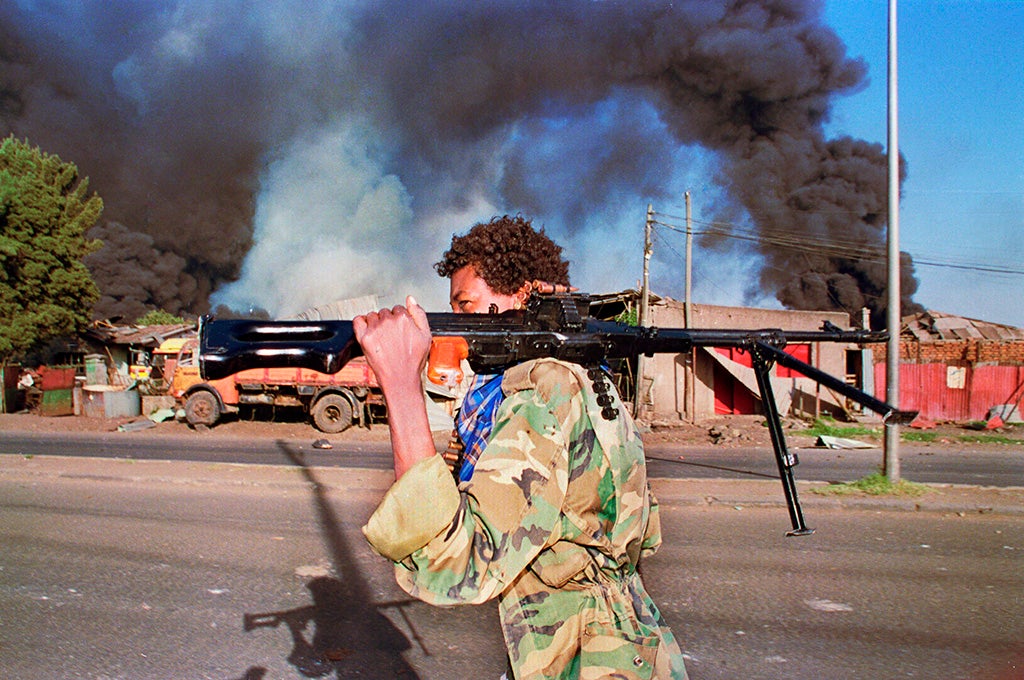 Un rebelde etíope portando una ametralladora delante de un edificio en el que acaba de impactar un proyectil (1991)