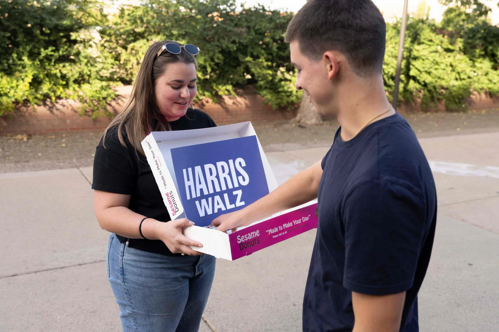 Una voluntaria de la campaña de Harris-Walz reparte donuts a los votantes que esperan en la cola del colegio electoral de la Universidad Estatal de Arizona