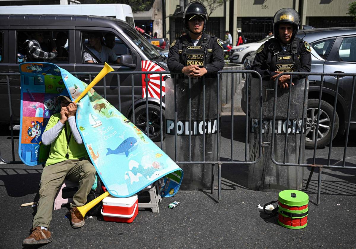 Un minero artesanal descansa junto a un par de policías antidisturbios mientras participa en una protesta frente al Congreso de Perú