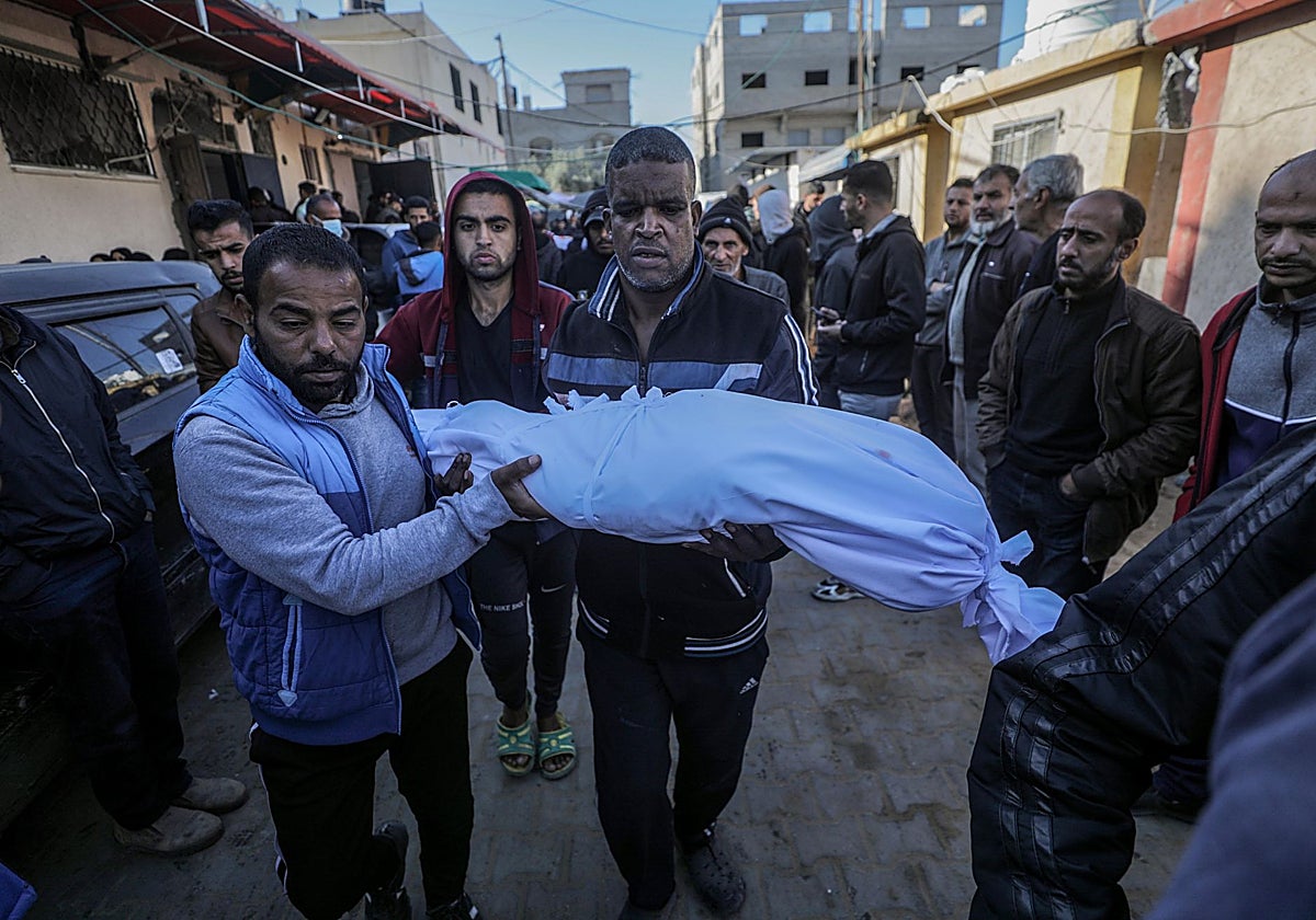 Un padre palestino carga con el cuerpo de su hijo durante el funeral en Hospital al-Aqsa, en la Franja de Gaza