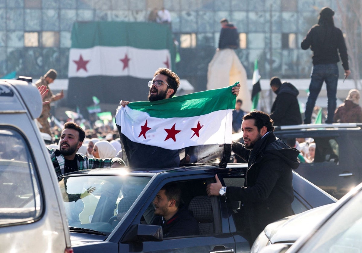 Un hombre sostiene una bandera adoptada por los nuevos gobernantes sirios, después de que Al Assad fuera derrocado, en el centro de Damasco